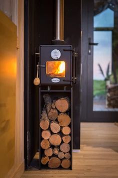 a wood burning stove in the corner of a room next to a stack of logs