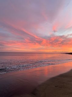 the sun is setting over the ocean with pink clouds