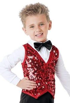 a young boy wearing a red sequin vest and black bow tie with his hands on his hips