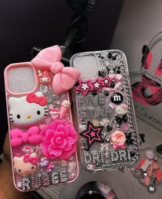 two cell phones with hello kitty designs on them, one is pink and the other is silver