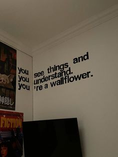 a television sitting on top of a wooden table in front of a wall with movie posters