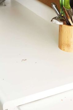 a cup filled with kitchen utensils sitting on top of a white countertop