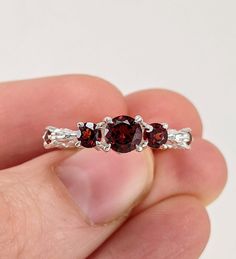 a close up of a person's hand holding a ring with three stones on it