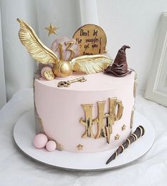 a pink and gold birthday cake with harry potter decorations