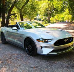 a white car parked on the side of a road next to some green trees and grass