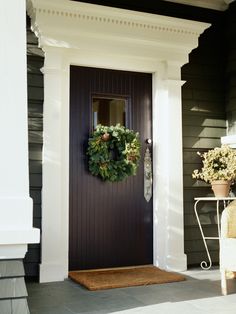 the front door is decorated with wreaths and potted plants