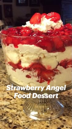 a trifle with strawberries and whipped cream in a glass dish on a counter