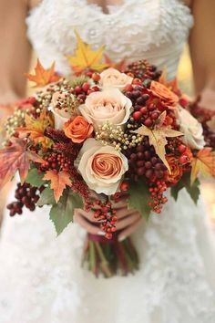 a bridal holding a bouquet of flowers and berries in her hands with leaves on it