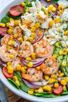 a salad with shrimp, tomatoes, corn and feta cheese in a white bowl