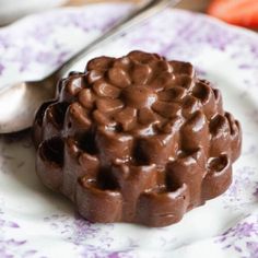 a chocolate dessert on a plate with strawberries in the background