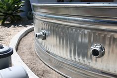 a large metal tank sitting on top of a cement ground next to a green plant