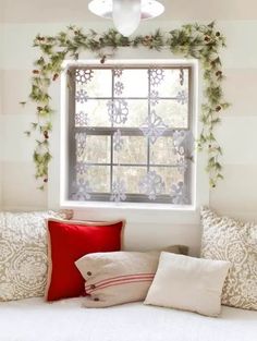 a bed with pillows and christmas decorations on the window sill