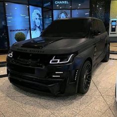 a black range rover parked in front of a chanel store