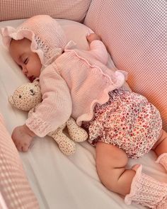 a baby sleeping in a crib with a teddy bear on it's side