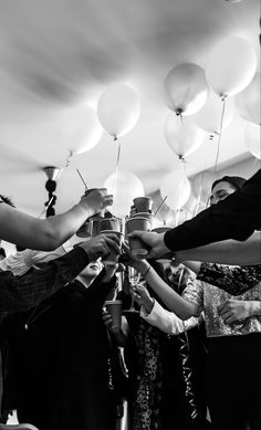 black and white photo of people holding balloons in the air with one person reaching for something