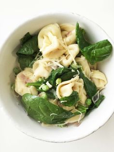 a white bowl filled with pasta and spinach