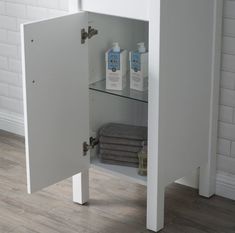 a bathroom cabinet with two bottles of hand sanitizers on the door and towels in front of it