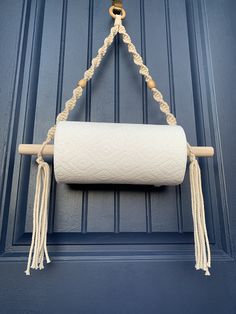 a roll of toilet paper hanging from a rope on a blue door with a wooden handle