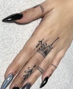 a woman's hand with black nail polish and tattoos on her left index finger