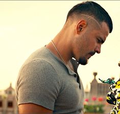 a man looking at his cell phone while standing next to a woman in a floral dress