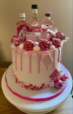 a cake decorated with pink and white icing, bottles of booze and candies