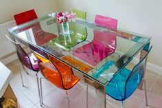 a glass table with colorful chairs around it