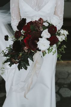 a bride holding a bouquet of red and white flowers