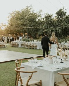 a bride and groom standing next to each other in front of tables with white linens