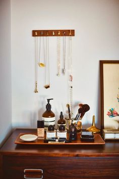 a wooden dresser topped with lots of personal care items next to a framed painting on the wall