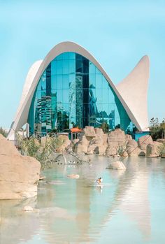 a large building that is next to a body of water with rocks in front of it