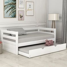 a white daybed with a trundle bed underneath it and a teddy bear on the floor