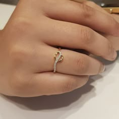 a woman's hand with a diamond ring on her finger and a pen in the background