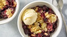 two bowls filled with ice cream and crumbled berry cobbler on a table