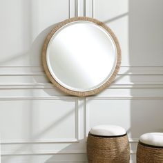 a round mirror hanging on the wall next to two stools