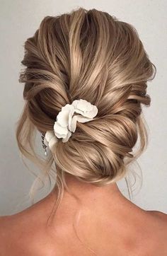 the back of a woman's head with blonde hair and flowers in her hair