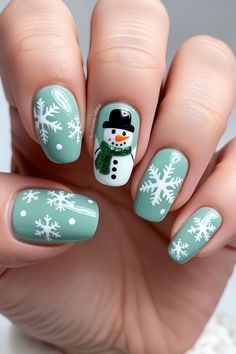 Get ready for the winter season with this adorable snowflake and snowman nail art! Featuring a minty green base, these nails are beautifully decorated with detailed white snowflakes and a cheerful snowman accent nail, complete with a black hat and a glittery green scarf. Perfect for anyone looking to add a touch of winter charm to their style, this nail design is both cozy and festive without the holiday focus. Embrace the frosty vibes with this cute winter nail idea! Snow Man Nails, Snowman Nails Design, Snowman Christmas Nails, Winter Snowflake Nails, Snowman Nail, Snowman Nail Art, Nails Medium Square, Nails Xmas, Christmas Press On Nails