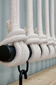 the rope is attached to the wall by two black hooks on each end and there are several white ropes in between them