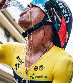 a man drinking water out of a bottle while wearing a helmet and holding his hands in the air