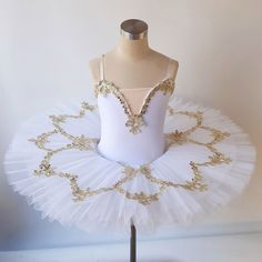 a white tutu with gold sequins on the top and bottom, sitting on a mannequin