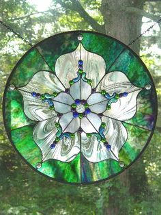 a stained glass window with white flowers in the center and green leaves on the outside