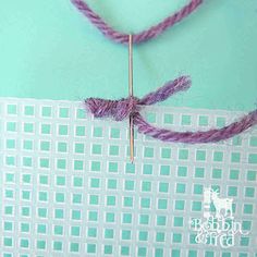 a piece of fabric is hooked up to a sewing needle with yarn on it and another piece of material in the background