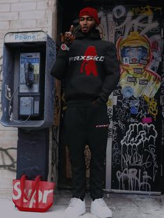 a man standing in front of a parking meter wearing a black sweatshirt and sweatpants