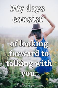 a woman in a blue dress and hat walking through flowers with her arms up to the sky