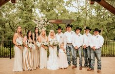 a group of people standing next to each other in front of a wooden structure with flowers