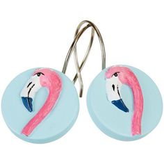 two pink flamingos are hanging from hooks on a white background, one is wearing a blue shirt and the other has a pair of scissors