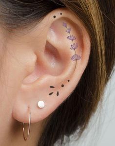 a woman's ear with flowers and leaves on the inside of her ear tattoo