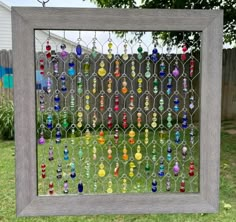 a window with many different colored glass beads hanging from it's sides in front of a house