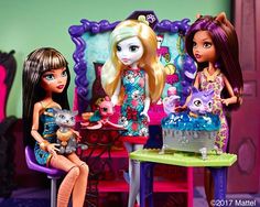 two dolls are sitting at a table with cats