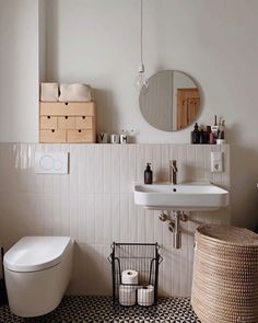 a bathroom with a white toilet, sink and basket on the floor next to it