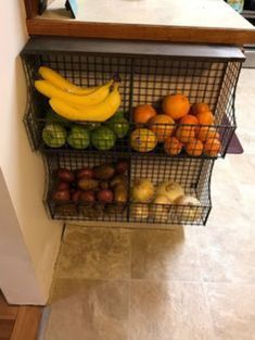 three wire baskets holding fruits and vegetables on a counter top next to a kitchen sink